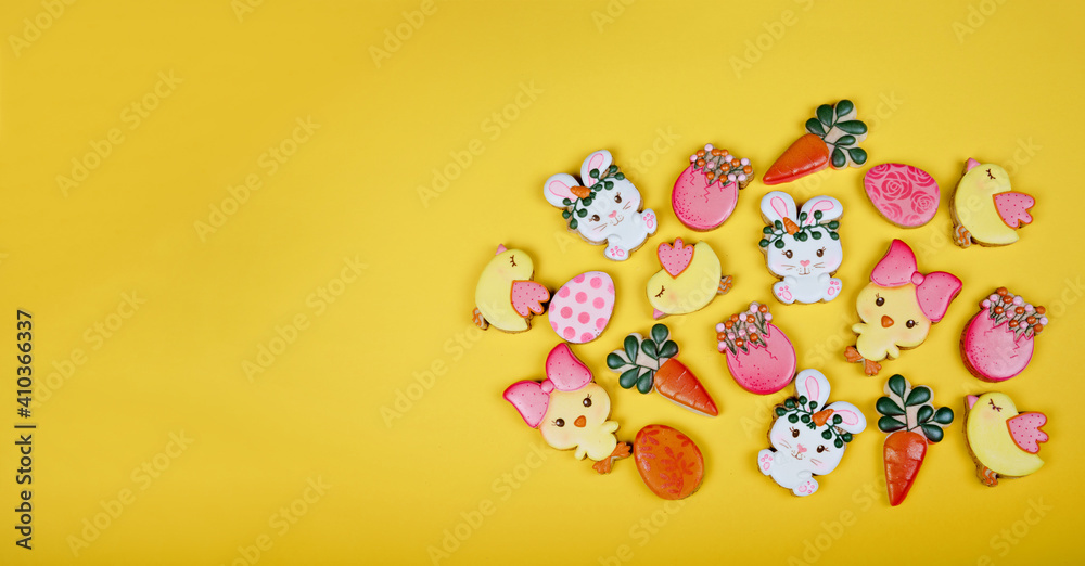Closeup of variation of different Easter sugar cookies decorated with royal icing. Eggs, bunny, carrots and chicken on yellow background. Lovely sweet gift or postcard