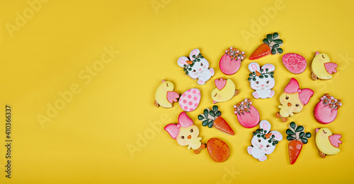 Closeup of variation of different Easter sugar cookies decorated with royal icing. Eggs, bunny, carrots and chicken on yellow background. Lovely sweet gift or postcard