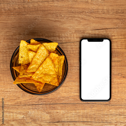 Nachos chips, smart phone  on a wooden background.