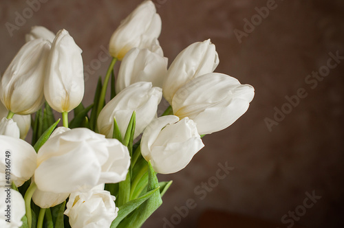 A bouquet of white tulips in a glass vase at home.