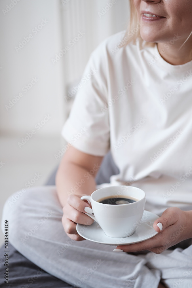 Young beautiful woman having breakfast in bed with coffee in cozy bedroom. Morning rituals. Close-up. Young beautiful woman having breakfast in bed with coffee in cozy bedroom. Morning rituals. Close-up.