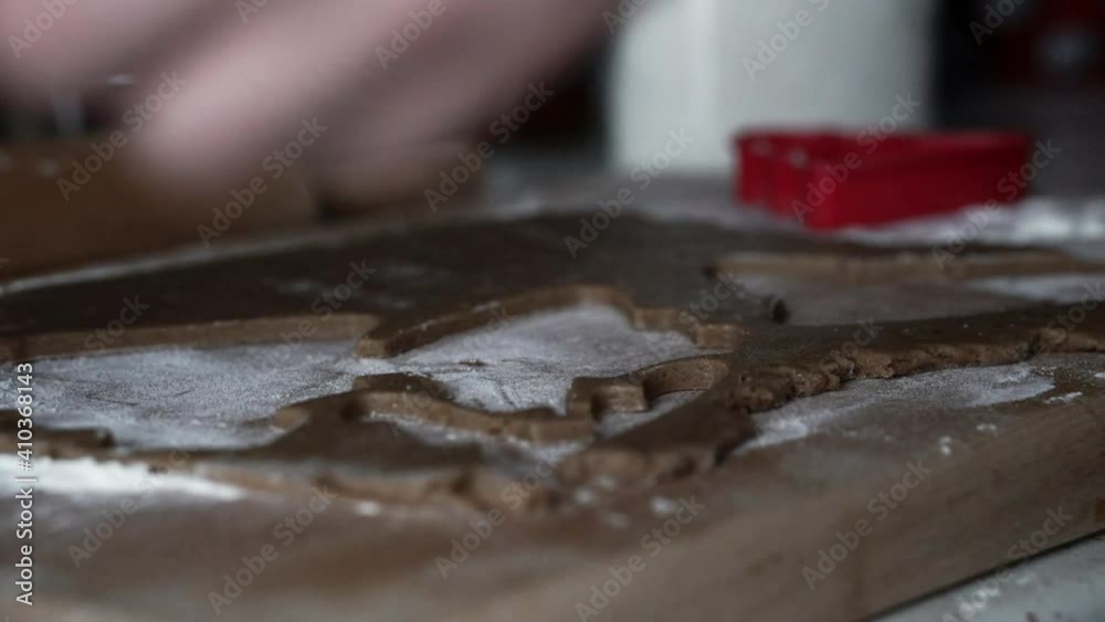 Caucasian female cutting Christmas tree out of gingerbread dough.