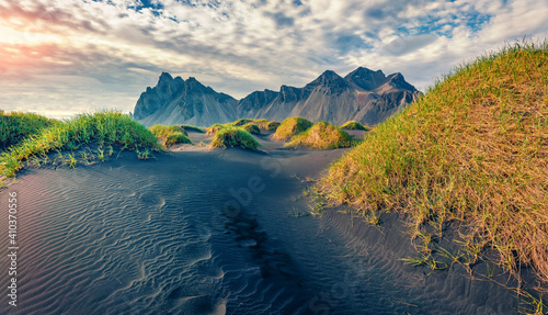 Beautiful summer scenery. Picturesque summer view of Stokksnes cape with Vestrahorn (Batman Mountain) on background. Icelandic landscape with black sand dunes and grass on top.