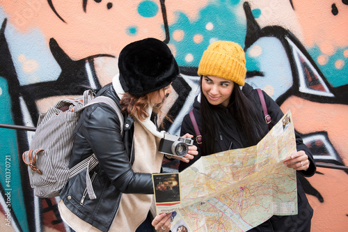 coppia di amiche in viaggio controlla la mappa davanti a un murales mentre decidono dove andare