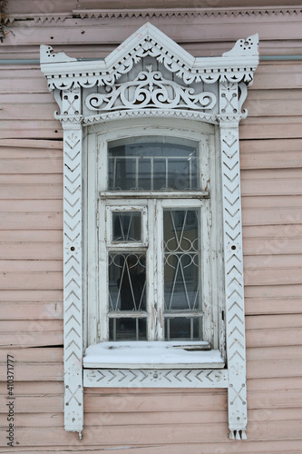 Ornamental window with carved frame on vintage wooden house on Shagova street, 22, Kostroma city, Russia. Building facade. Russian traditional national folk style in architecture. Russian landmark photo