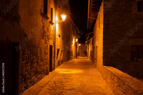 Night view of narrow street in old village of Rupit near Barcelona, Spain.Touristic destination concept, empty rustic alley with street lights background.