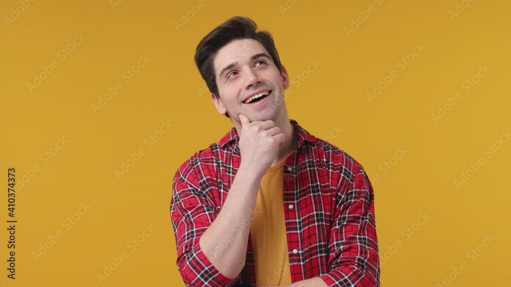 Pensive cheerful young man 20s years old wearing casual red checkered shirt posing isolated on yellow background in studio. People emotions lifestyle concept. Looking aside up put hand prop up on chin Pensive cheerful young man 20s years old wearing casual red checkered shirt posing isolated on yellow background in studio. People emotions lifestyle concept. Looking aside up put hand prop up on chin