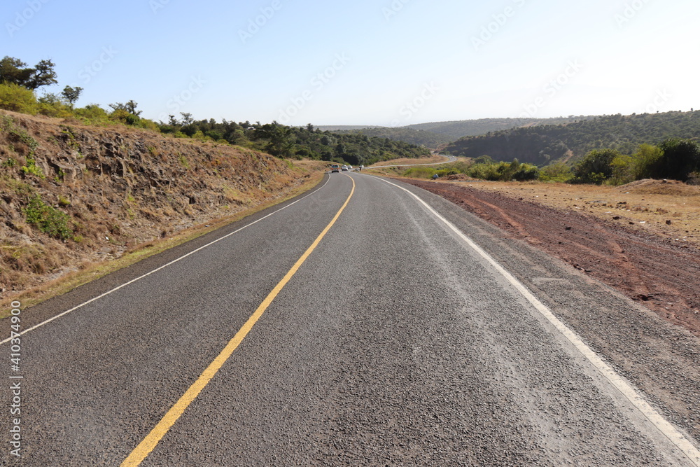 An asphalt tarmac road cuts through the countryside along the equator in Nyeri-Laikipia, Kenya. 