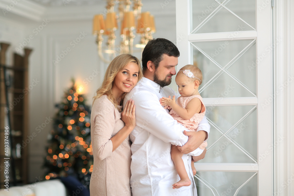 beautiful blond family mother, father and daughter are beard behind the house is decorated with Christmas tree beautiful blond family mother, father and daughter are beard behind the house is decorated with Christmas tree
