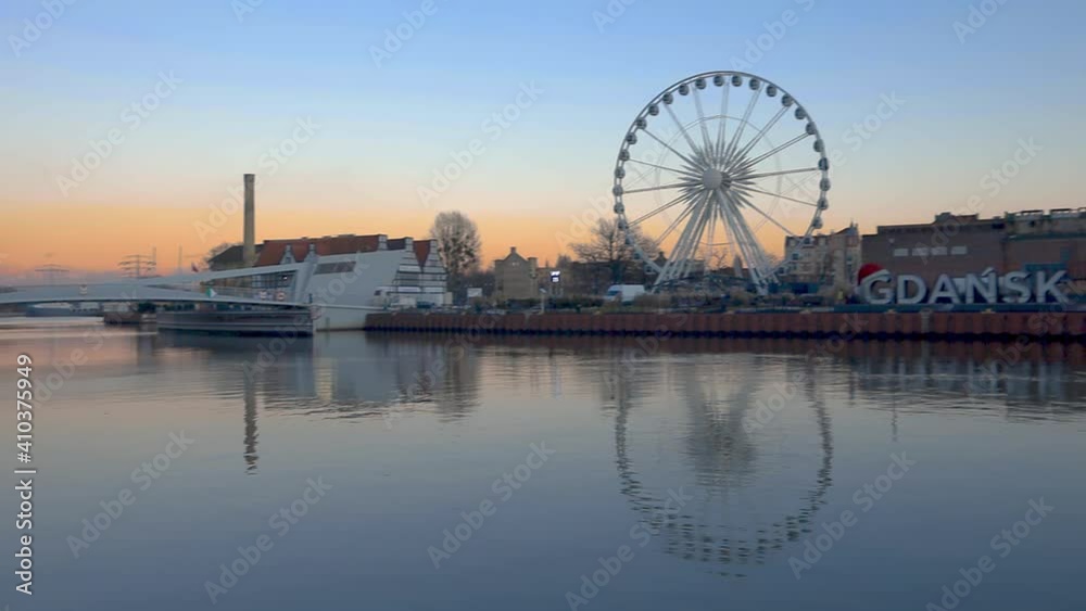 ferris wheel and Gdansk name label near river, panning shot of riverside buildings and street Gdansk Poland ferris wheel and Gdansk name label near river, panning shot of riverside buildings and street Gdansk Poland