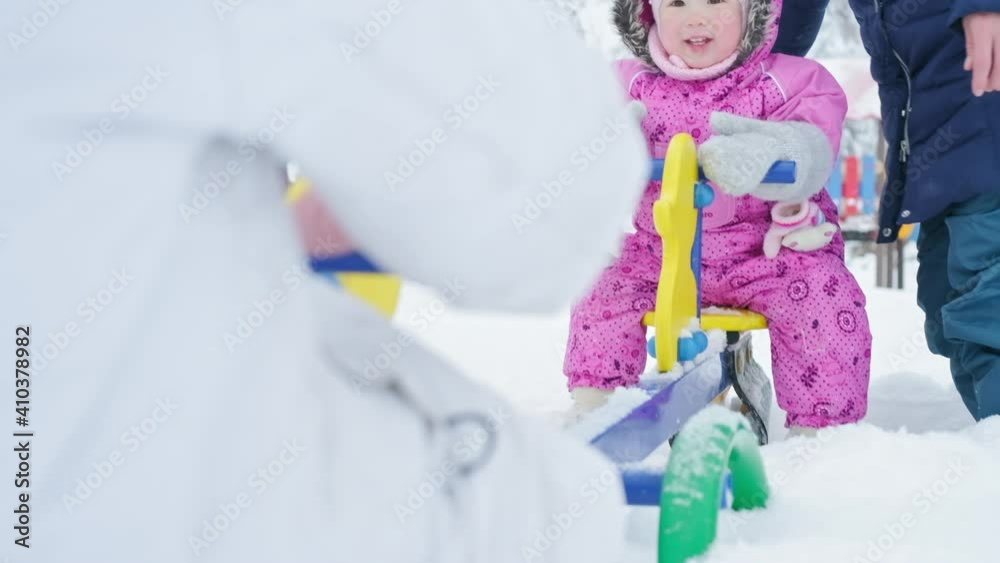 Family on swing. Toddler girl sits on the swing with her older sister and mother and has fun Family on swing. Toddler girl sits on the swing with her older sister and mother and has fun