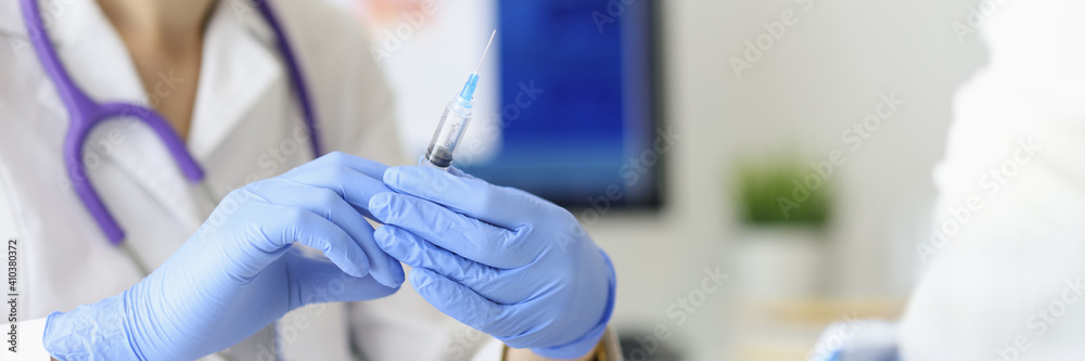 Doctor's hands hold syringe with needle next to the patient. Medical assistance concept Doctor's hands hold syringe with needle next to the patient. Medical assistance concept