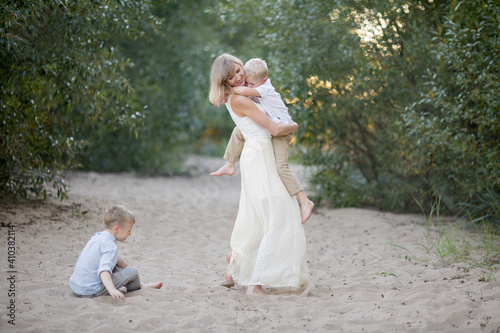 mother in a long dress holding her son and eldest son catches up with them