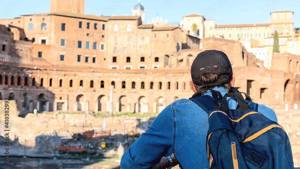Tourist man with backpack looking at Italic historical ruins.