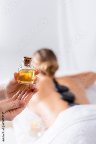 cropped view of masseur holding bottle with oil near client