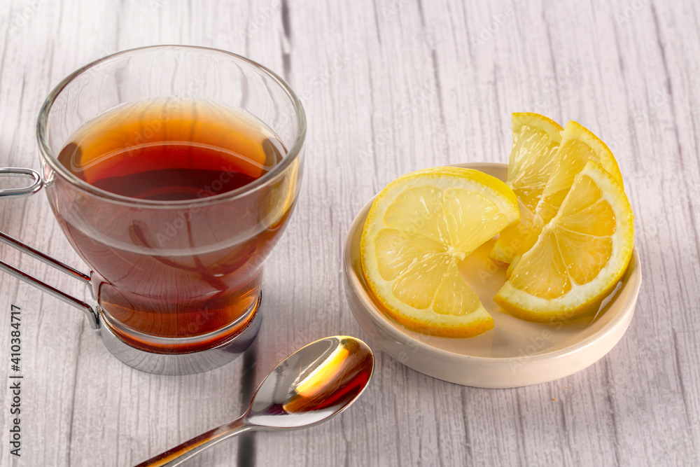 Cup of tea on wooden surface in light tone and white background, lemon slices and teaspoon. tea time concept