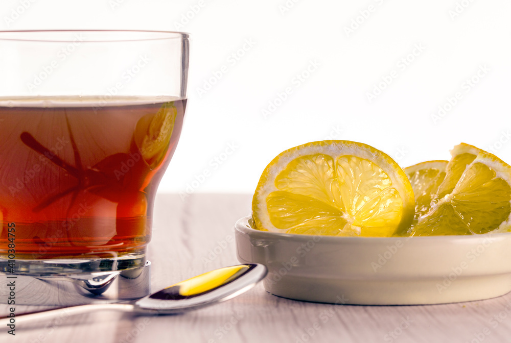 Cup of tea on wooden surface in light tone and white background, lemon slices and teaspoon. tea time concept Cup of tea on wooden surface in light tone and white background, lemon slices and teaspoon. tea time concept