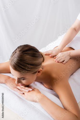 masseur massaging back of client lying on massage table