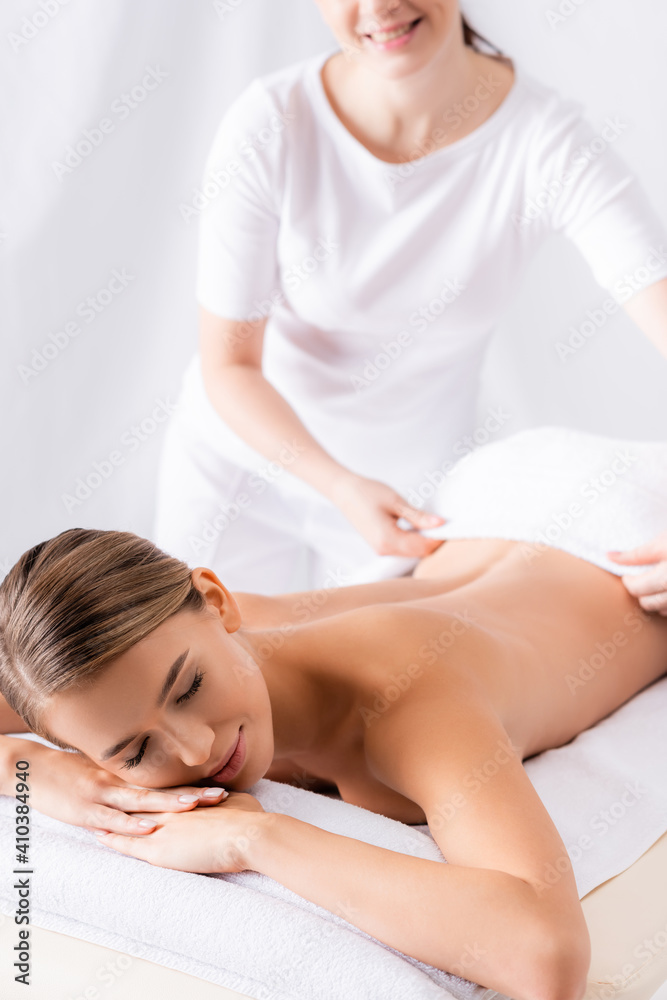 masseur adjusting towel on beautiful client lying on massage table masseur adjusting towel on beautiful client lying on massage table