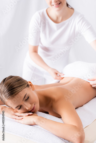 masseur adjusting towel on beautiful client lying on massage table