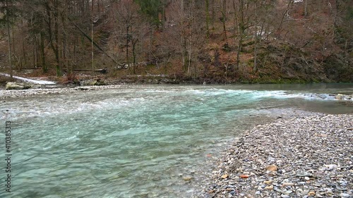 Pristine and clean water flowing downstream in Slovenia. Blue river in forest. Calm stream flowing in Alpine valley. Static shot, real time, wide angle