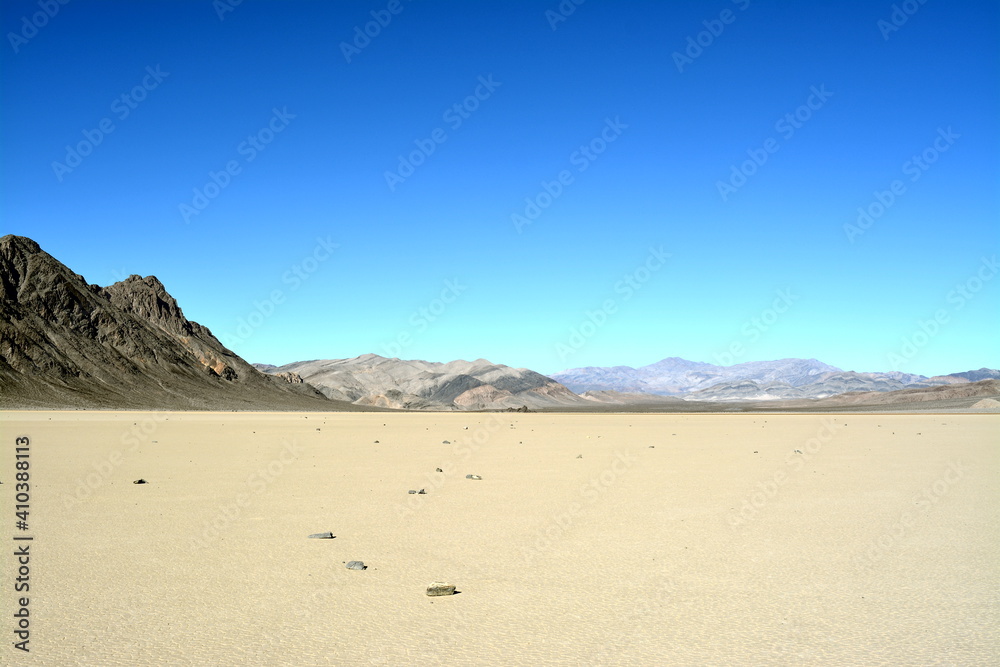 moving stones on the Racetrack Playa leaving tracks in the dry and cracked terrain in the Death Valley National Park, recflections of the sun