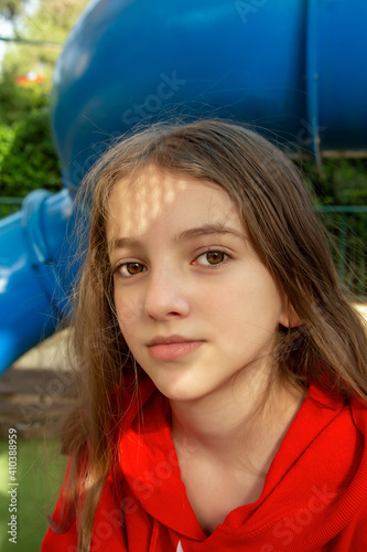 portrait of teenage girl with loose hair on city playground on sunny day