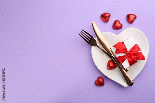 Beautiful table setting on violet background, flat lay with space for text. Valentine's Day dinner