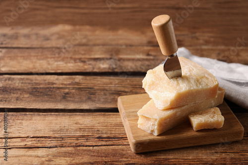 Delicious parmesan cheese with knife on wooden table. Space for text