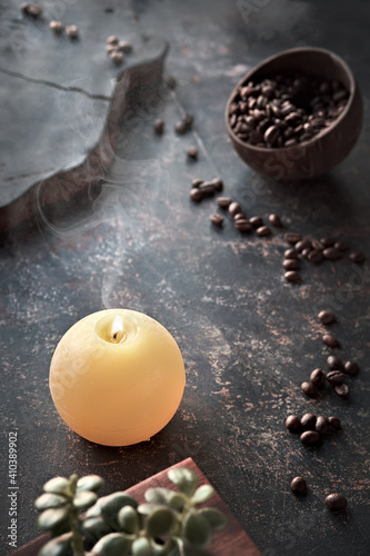 Moody dark background with coffee beans in coconut bowl and succulent plant on aged textured background. Distressed grunge, retro style toned. Delicious, aromatic, refreshing mixture of smells, aroma.
