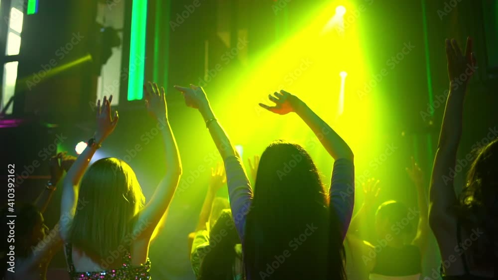 Group of Asian woman friend dancing dj club music with multi-color illuminated neon night lights at night club. Fashionable female enjoy and having fun with nightlife dance party at disco nightclub.