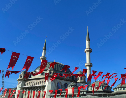 Blue sky over Mosque with tower with red Turkish flags in Istanbul, Turkey. Mosque Minarets, Selective focus shallow depth of field. Flags are fluttering in the wind.
