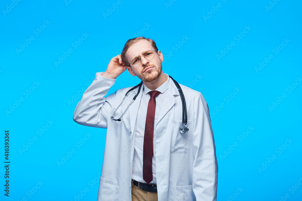Medical concept of professional male doctor brooding teacher. Medical student general practitioner. Man hospital worker looking at camera, studio, blue background. Medical concept of professional male doctor brooding teacher. Medical student general practitioner. Man hospital worker looking at camera, studio, blue background.