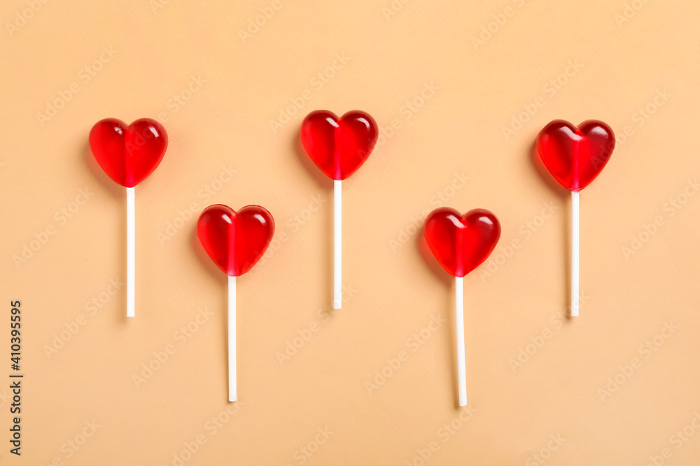 Sweet heart shaped lollipops on beige background, flat lay. Valentine's day celebration