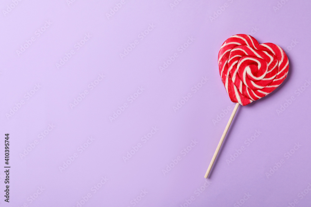 Sweet heart shaped lollipop on violet background, top view with space for text. Valentine's day celebration Sweet heart shaped lollipop on violet background, top view with space for text. Valentine's day celebration