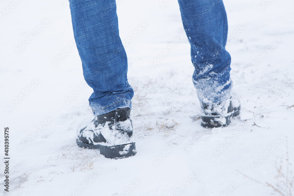 men's feet in boots in the snow walking in winter men's feet in boots in the snow walking in winter