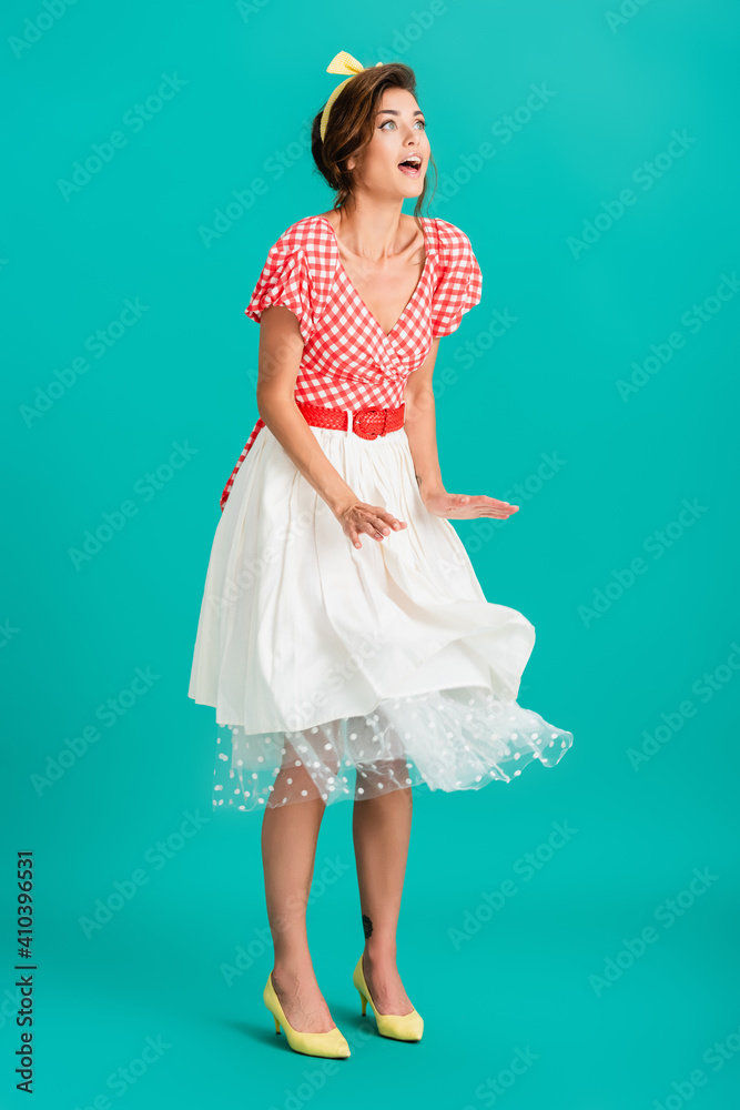 amazed pin up woman looking away while standing on wind on turquoise amazed pin up woman looking away while standing on wind on turquoise