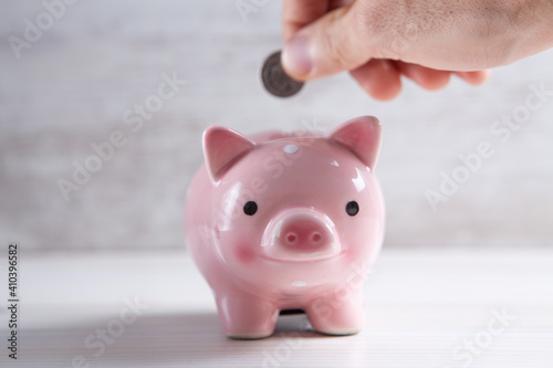 Young woman  putting a coin inside piggy bank as savings for investment © S...