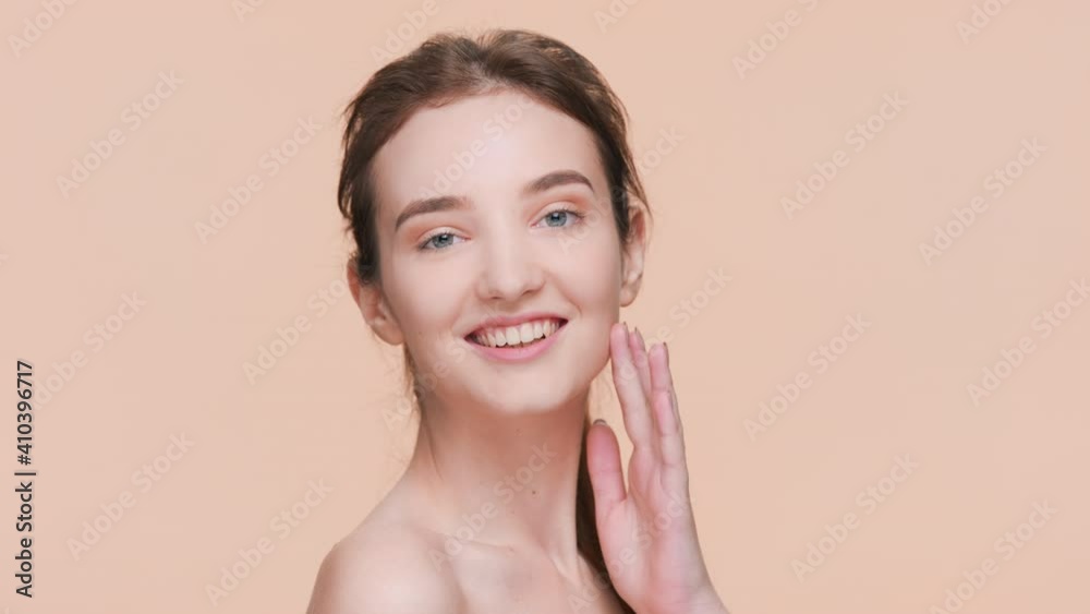 Young good-looking positive brunette woman with a ponytail turns to the camera, touches her soft skin and smiles | Skin care and beauty care product commercial concept Young good-looking positive brunette woman with a ponytail turns to the camera, touches her soft skin and smiles | Skin care and beauty care product commercial concept