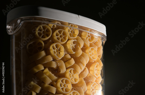 Close up view of jar full with Rotelle Wagon wheel-shaped pasta against dark background photo