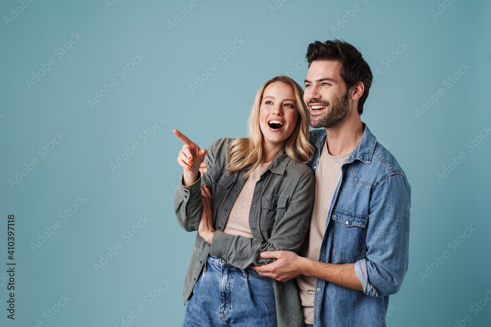 Young beautiful excited man and woman hugging and pointing finger Young beautiful excited man and woman hugging and pointing finger