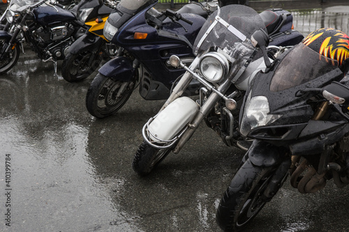 Motorcycles parked in row in the rain.