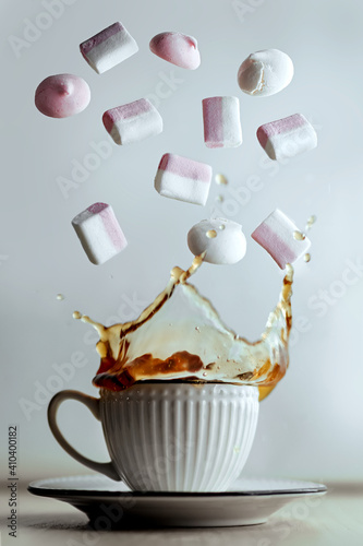 pink and white marshmallow flying above the cup of tea. splashing beverage. sweet concept. levitation food, sweet dessert, flying marshmallow. white background.
