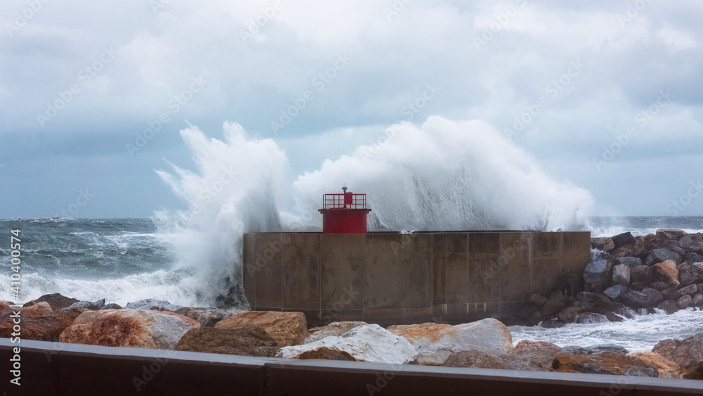 Fototapeta premium Breaking wave over the harbor light