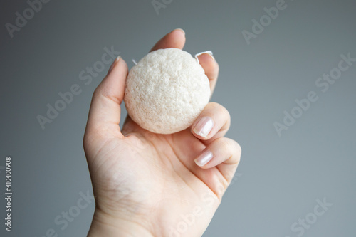 Natural konjac sponge in a female hand for deep cleanse and exfoliate skin. Healthy lifestyle, zero waste cosmetic routine. 
