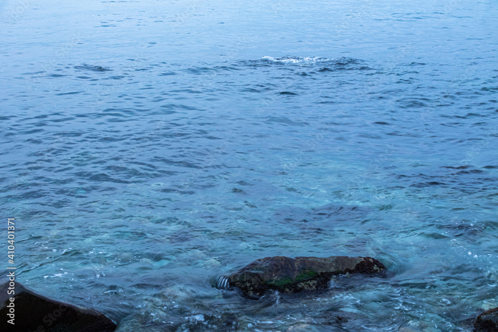 Obraz premium beautiful, blue sea with waves, foam, rocks at the beach in good weather in the evening