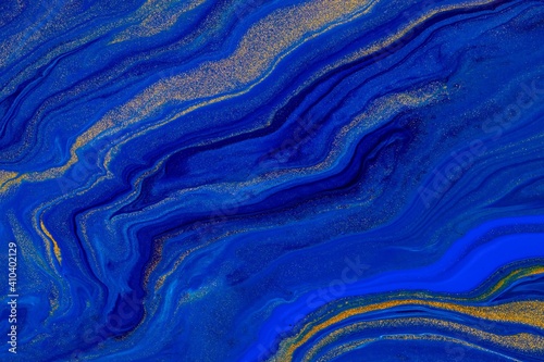 Fluid art texture. Background with abstract iridescent paint effect. Liquid acrylic picture with flows and splashes. Classic blue color of the year 2020. Blue, golden and indigo overflowing colors
