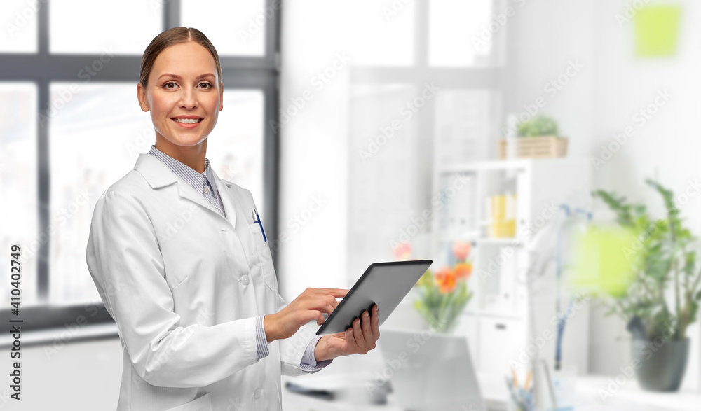 medicine, profession and healthcare concept - happy smiling female doctor in white coat with tablet pc computer over medical office at hospital on background
