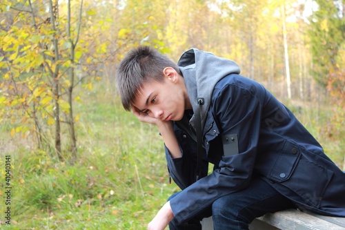 Sad teenage boy sitting on a bench alone