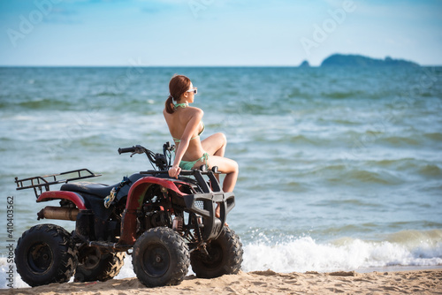 Asian young beautiful woman model in a bikini pose with ATV bike at the beach.summer vacation.